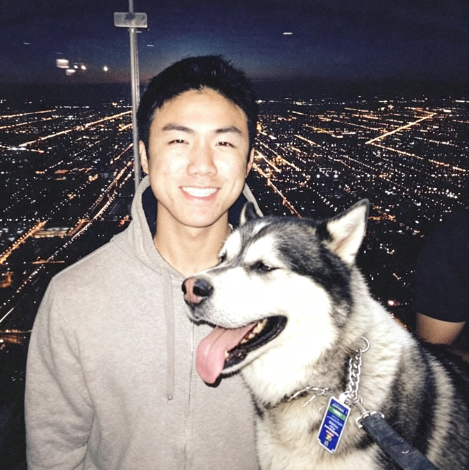 Robert smiling beside Bobby, his dog, against a nighttime city view.
